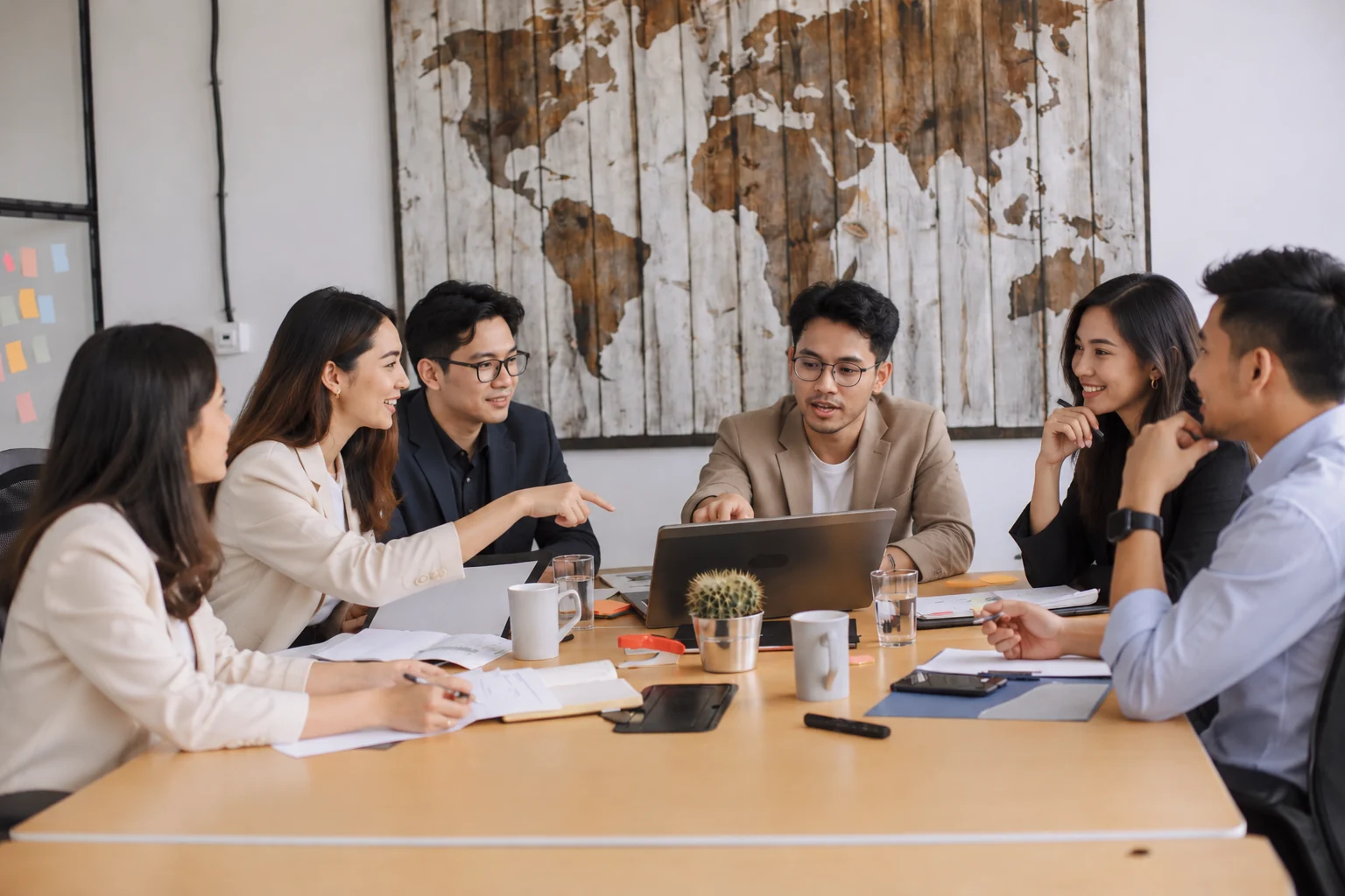 Professionals collaborating around a laptop at a meeting table