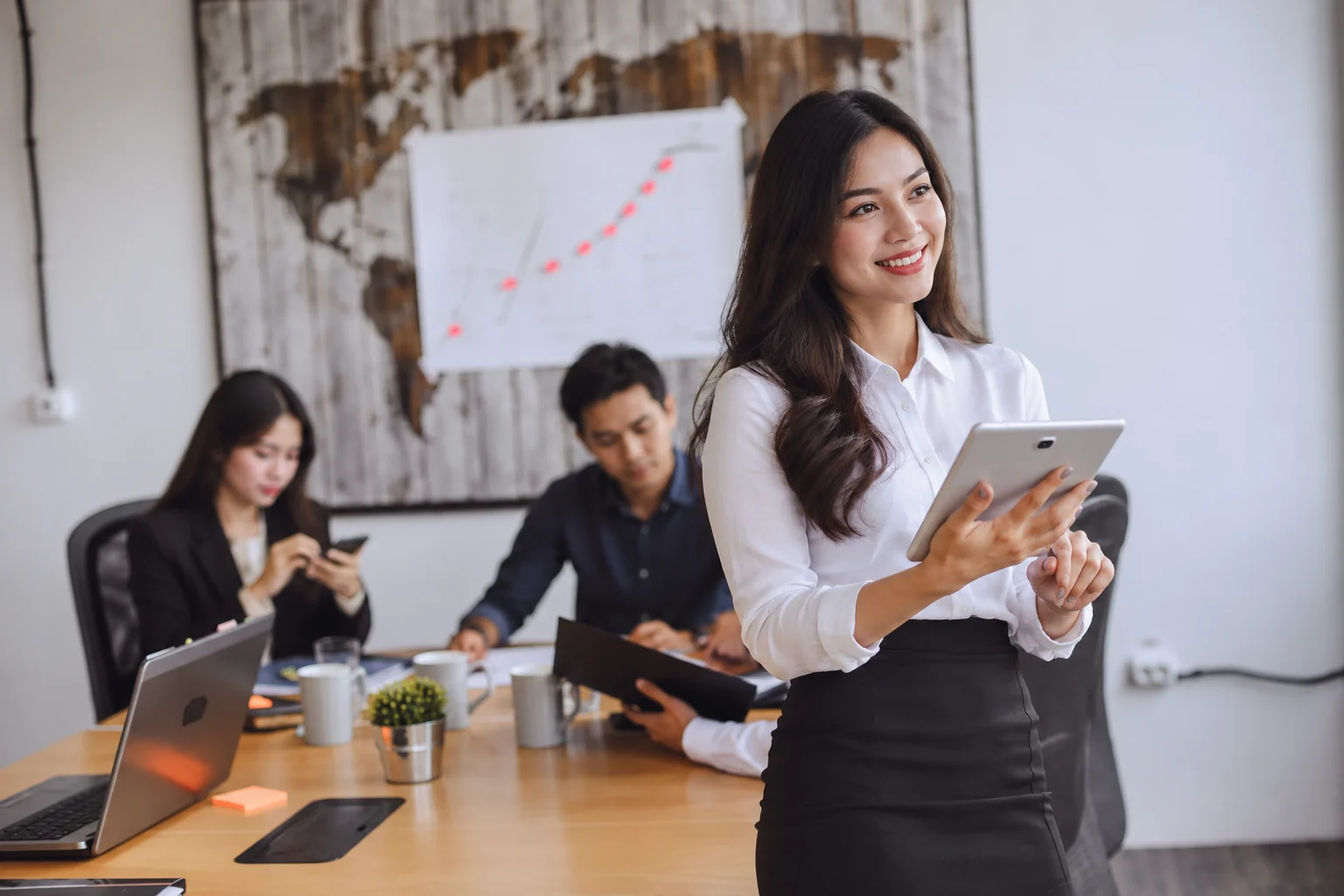 A smiling professional with a tablet in a meeting room